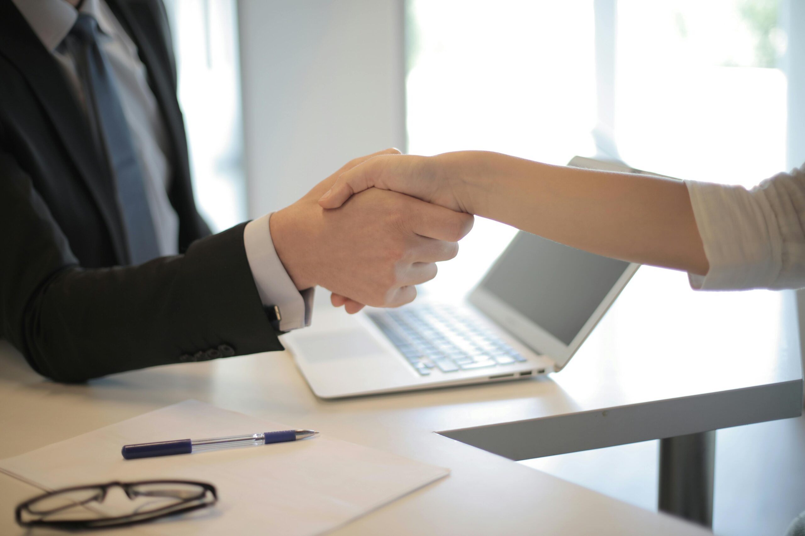 Home Close-up of a professional handshake over a laptop during a business meeting in an office.